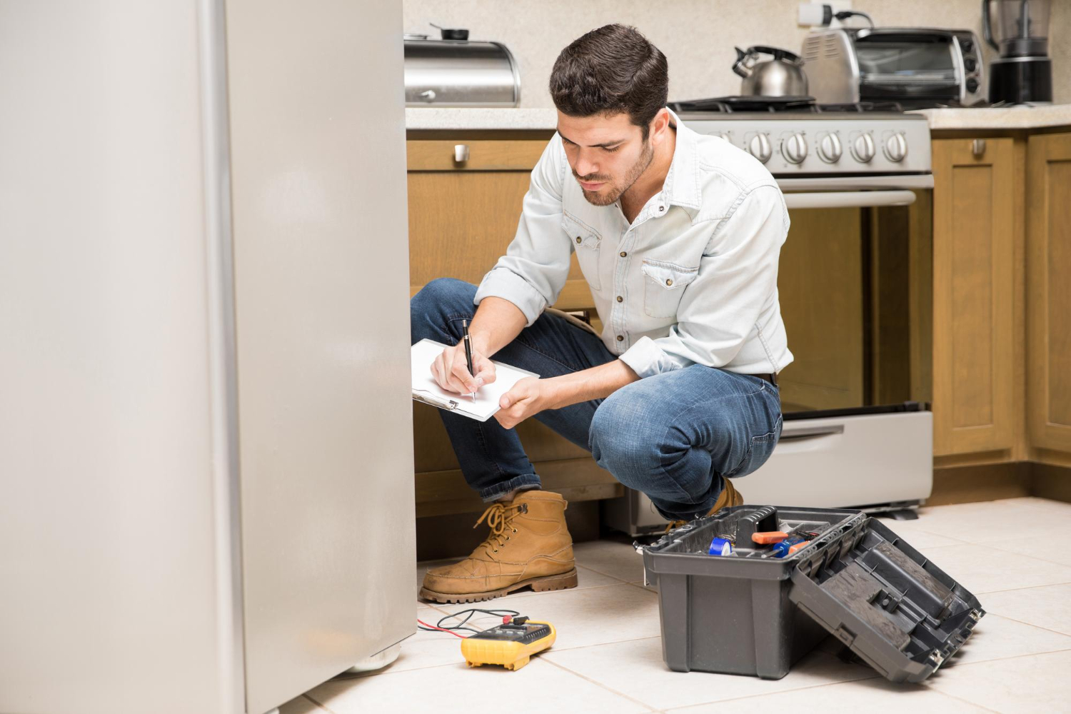 portrait-handsome-male-technician-doing-work-report-broken-fridge-home-kitchen